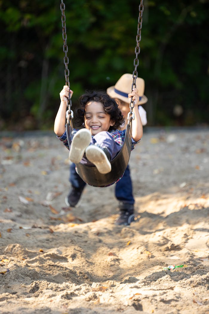 Happy children playing on a swing set outdoors in a sunny park setting, enjoying a carefree day.