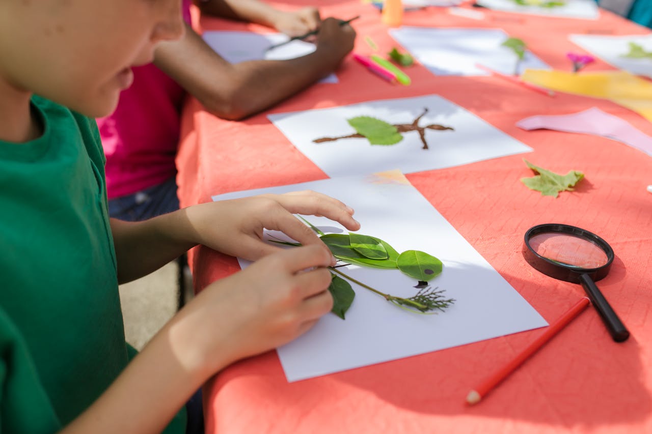 Children create leaf art at summer camp, exploring creativity with natural materials.